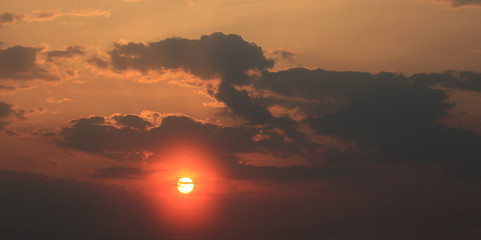 Red sunlight from behind dark clouds in the evening sky at sunset