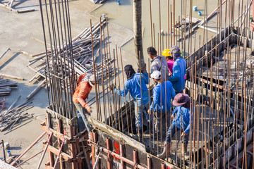 Worker pouring cement pouring into foundations and pillars formwork at building area in construction site. - obrazy, fototapety, plakaty