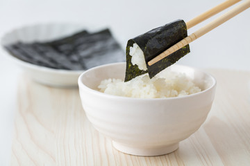 白背景に白いご飯に海苔を巻いて食べる日本人お米日本食 - obrazy, fototapety, plakaty