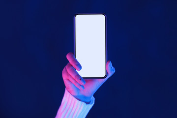 Woman's hand showing smartphone screen in neon lights