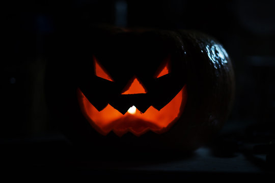 creepy smiling pumpkin for Halloween on black background.