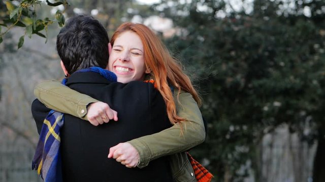 mischievous woman hugging herboyfriend  at the park and flirts with the camera