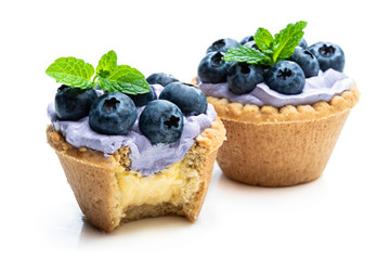 Mini tarts with blue cream and fresh blueberries isolated on white background