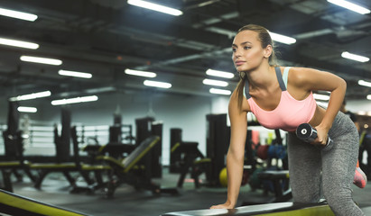 Sporty girl working out with weights in sport club