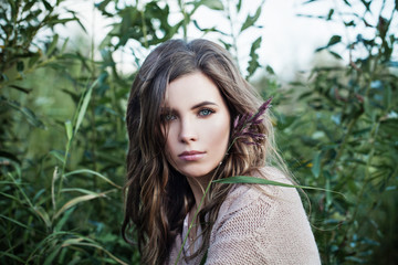 Pretty woman with healthy skin and brown curly hair on green grass background