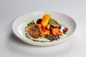 Food on white plate. Meat. Tomatoes. eggplants. Greenery. Cheese.