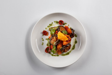 Food on white plate. Meat. Tomatoes. eggplants. Greenery. Cheese.