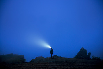 Silhouette of man with headlamp in foggy dusk
