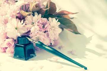 Old ink pen and ink bottle on white background. Vintage calligraphy pen and bottle of ink. Cherry blossom twig with black ink