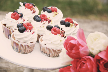 Homemade pavlovas cupcakes with berries and tulips