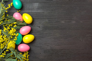 Obraz premium Easter background with mimosa, eggs and wooden surface