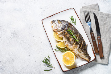 Baked dorado fish with lemon and rosemary top view.