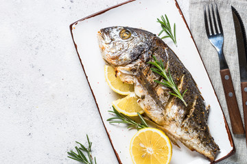 Baked dorado fish with lemon and rosemary top view.