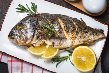 Baked dorado fish with lemon and rosemary top view.