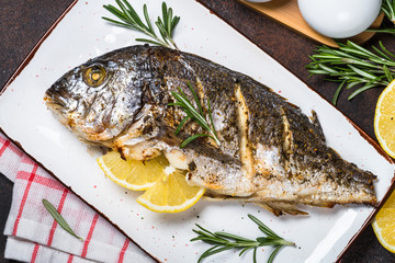 Baked dorado fish with lemon and rosemary top view.