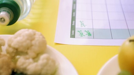 Keeping a fitness calendar.concept of healthy food, diet, top view, yellow background