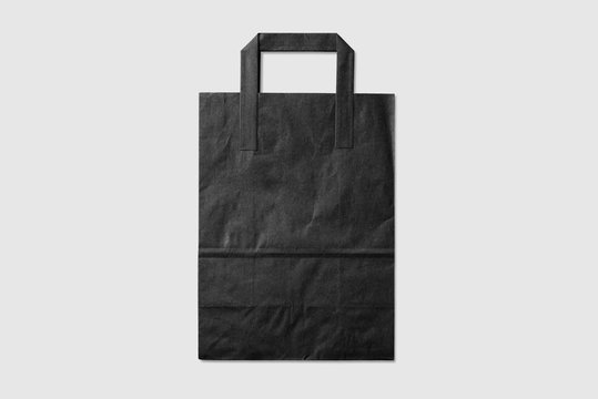 Mockup Of A Blank Black Paper Shopping Bag With Handles On Light Grey Background. High Resolution.