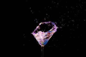 Splash Photography. Burst of Colorful Liquid in Wine Glass. Isolated Over Black.