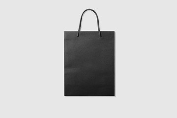 Mockup of a blank black paper shopping bag with handles on light grey background. High resolution. - Powered by Adobe