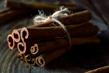 Tied dried cinnamon sticks on rustic wooden table - selective focus