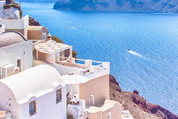 Fototapeta na wymiar World Famous Travel places. Amazing and Stunning View of Oia Village in Santorini Island in Greece. Located Over Caldera Mountains with Boats on Background.
