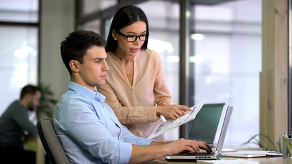 Colleagues entering data from graphs into computer to check growth and decline