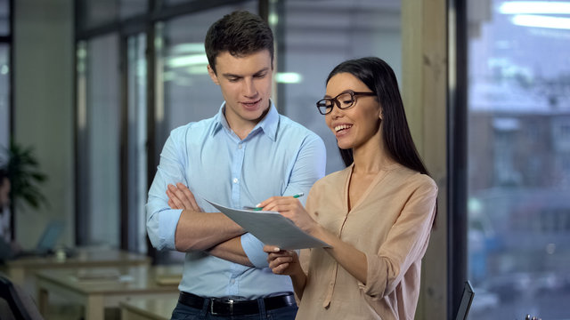 Cheerful creative designers discussing order, asian woman making notes paper