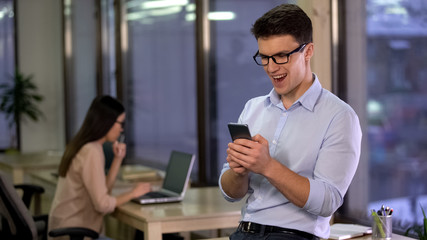 Excited man using smartphone application in office, modern technology, gadget