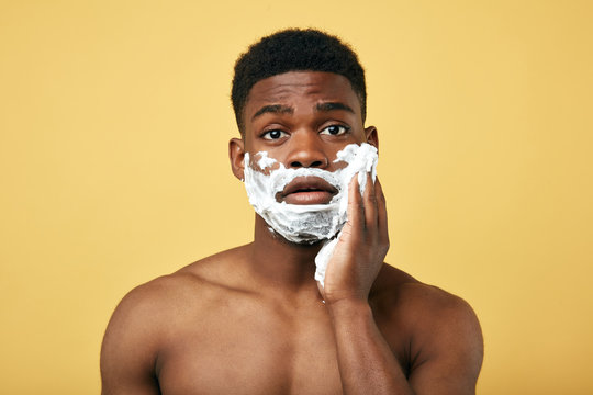 grooming concept. Puzzled African man going to shave beard, poses half naked,daily routine. pastime