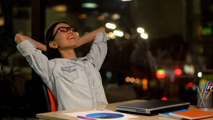 Happy woman relaxing on chair, satisfied with productive working day, freelance