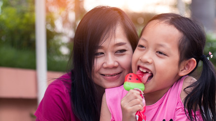 Asian mother and her daughter smiling with eating ice cream