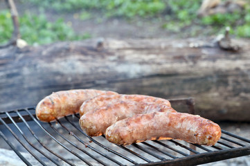 Pork sausages are roasted on the coals on the grill.