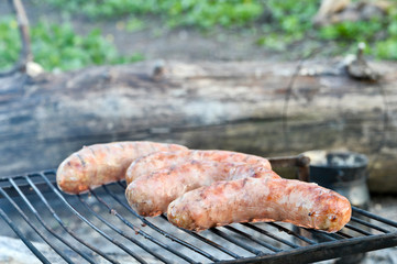 Pork sausages are roasted on the coals on the grill.