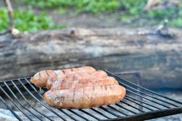 Pork sausages are roasted on the coals on the grill.