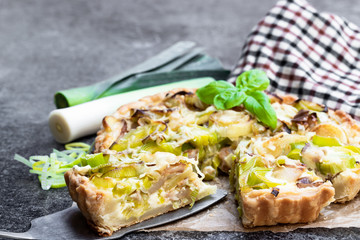 Leek tart with bacon and cheese on wooden table