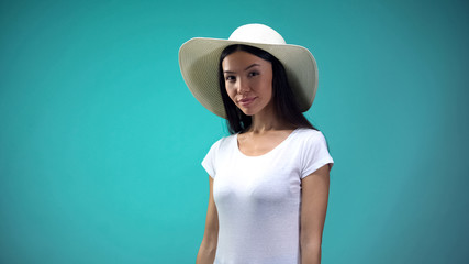 Pretty woman in big hat looking at camera, isolated on blue background, vacation