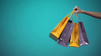 Female hand holding many colorful shopping bags on blue background, template - 264922838
