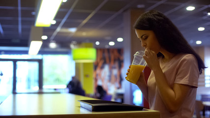 Brunette woman drinking fresh orange juice from plastic glass, antioxidant diet