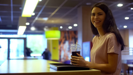 Smiling young woman holding cocktail plastic glass, refreshing carbonated water
