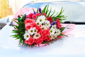 A bouquet of flowers is located on the car. natural lighting. flowers of roses and daisies.