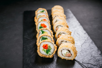 sushi, japanese food, deluxe restaurant menu, delicious traditional seafood. philadelphia and vegetarian tempura sushi rolls, served on black plate