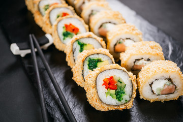 Tempura maki. Japanese sushi tempura roll on black slate. Japanese traditional fusion food style, restaurant menu