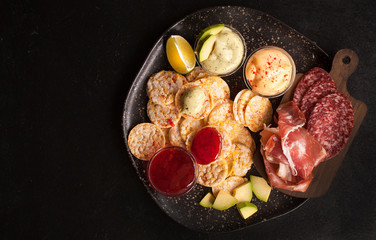 Sandwiches of whole grain bread with ham, bacon, prosciutto, olives and olives with whole grain chips on a black wooden background. Clean food, healthy Breakfast. Top view with copy space
