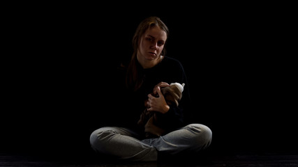 Crying depressed lady hugging teddy bear in darkness, obstetric violence victim
