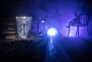 Time concept. Silhouette of a man standing between hourglasses with smoke and lights on a dark...