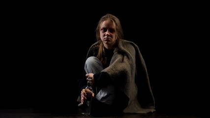 Depressed alcoholic female sitting in darkness with bottle of vodka, addiction