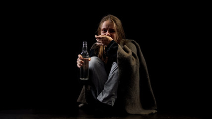 Obraz premium Depressed alcohol addicted woman drinking vodka from bottle, looking with hatred