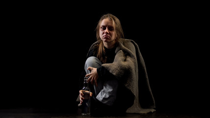 Miserable woman with bottle of vodka isolated on black, alcohol addiction