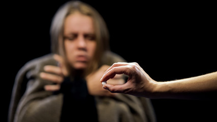 Hand offering ecstasy to woman suffering withdrawal symptoms, drug addiction