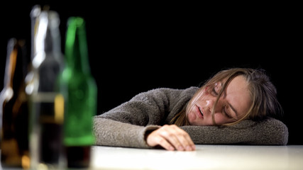Obraz premium Addicted female sleeping on table after drinking alcohol, harmful health effect